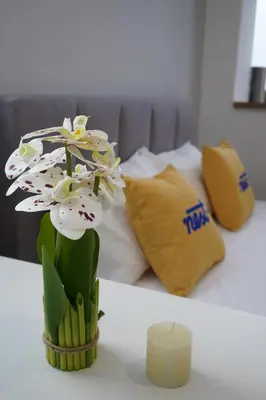 a vase with white flowers on a table with a candle at Riveria City KL Sentral by Nest Suite in Kuala Lumpur