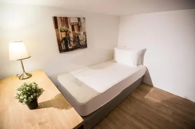 a small room with a bed and a table with a lamp at Bangsar LRT Suites EST by LSA in Kuala Lumpur
