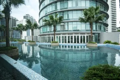 a swimming pool in front of a building with palm trees at Vortex KLCC by LSA in Kuala Lumpur