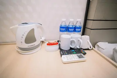a coffee maker and cups and water bottles on a table at Swing & Pillows - TAR UMT Setapak in Kuala Lumpur
