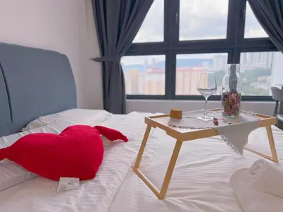 a red heart pillow sitting on a bed with a table at ISYAK Homestay Cheras M Vertika KL in Kuala Lumpur
