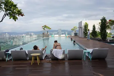 a swimming pool on the roof of a building with people sitting around it at Riveria City KL Sentral by Nest Suite in Kuala Lumpur