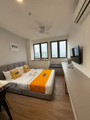 a bedroom with a large bed with an orange blanket at Nest Suites By KL in Kuala Lumpur