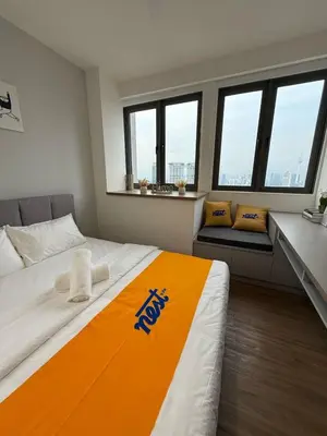 a bedroom with a large bed with an orange blanket at Nest Suites By KL in Kuala Lumpur