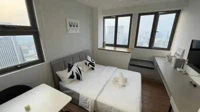 a room with a bed and a desk with windows at Nest Suites By KL in Kuala Lumpur