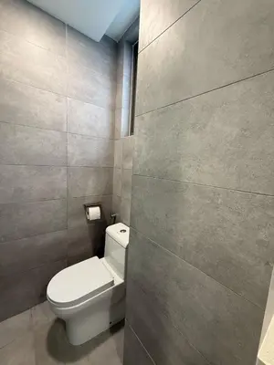 a bathroom with a white toilet and a wall at Nest Suites By KL in Kuala Lumpur
