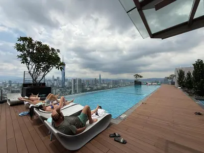 a group of people laying on lounge chairs next to a swimming pool at Nest Haven KL in Kuala Lumpur