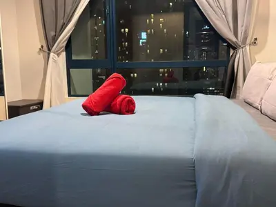 a red teddy bear laying on a bed with a window at Casa residency by relaxhome in Kuala Lumpur