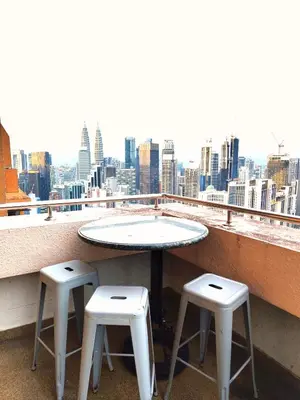 a table and two stools on a balcony with a view at Twobedroom Hotel Apartment At Times Square Kuala Lumpur in Kuala Lumpur