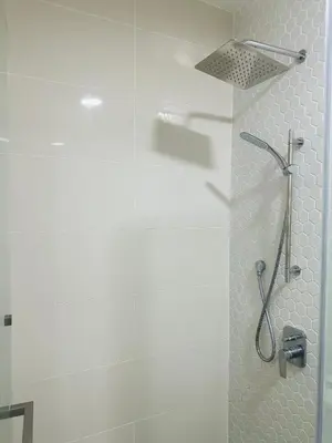a shower in a bathroom with white tiles at In