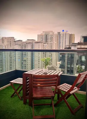 a table and chairs on a balcony with a city skyline at Arcoris Mont Kiara in Kuala Lumpur