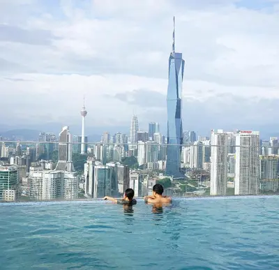 two people in a infinity pool with a view of the city at Riveria City Kuala Lumpur in Kuala Lumpur
