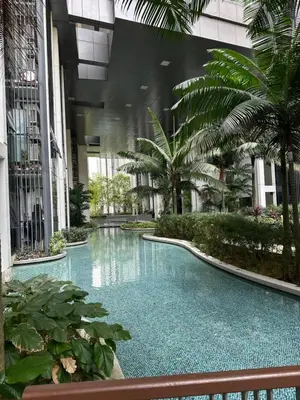 a swimming pool in the middle of a building with palm trees at MCity Studio With Balcony, Near KLCC, Gleneagles Hosp, Ampang Puteri Hosp in Kuala Lumpur
