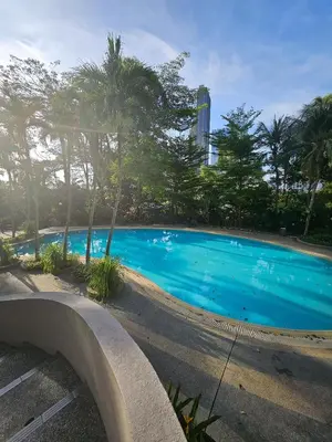 a large blue swimming pool with trees and a building at X'Apartelle near Pusat Bandar Damansara MRT in Kuala Lumpur