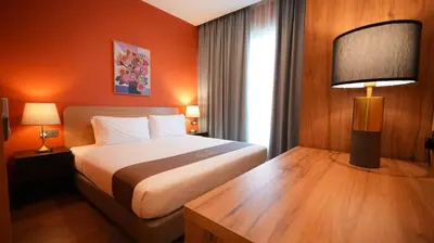 a hotel room with a bed and a desk with a lamp at Acappella Kuala Lumpur City Centre in Kuala Lumpur