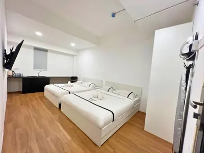 a white bedroom with a large bed and a kitchen at Seeds Hotel Premier Chow Kit Kuala Lumpur in Kuala Lumpur