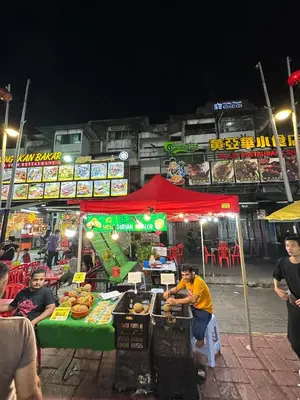 a man sitting at a food stand at night at SS Grey House Bukit Bintang in Kuala Lumpur