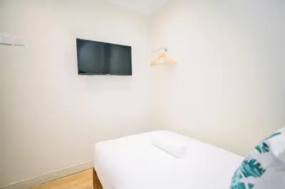a living room with a white couch and a tv at Swing & Pillows - Sungei Wang Bukit Bintang in Kuala Lumpur