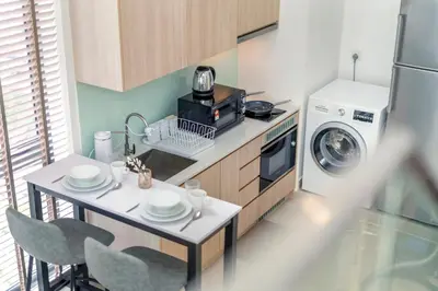 a small kitchen with a table and a washing machine at The Colony & Luxe Kuala Lumpur with KLCC View Skypool by COBNB in Kuala Lumpur