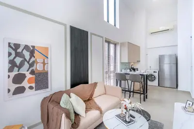 a living room with a couch and a kitchen at The Colony & Luxe Kuala Lumpur with KLCC View Skypool by COBNB in Kuala Lumpur