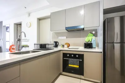 a kitchen with white cabinets and a black oven at Trion Kuala Lumpur by Vivid Stay in Kuala Lumpur