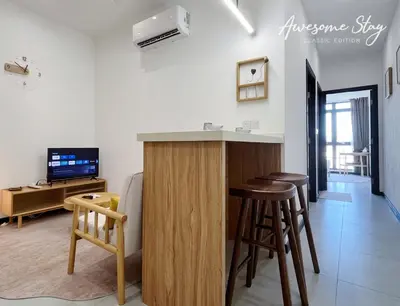 a kitchen and living room with a bar and stools at Neu Suites By The Relaxstay in Kuala Lumpur