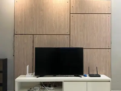 a television on a white table with a wooden wall at Regalia Residences and suits By Comfortcorner in Kuala Lumpur