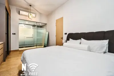 a bedroom with a large white bed and a glass door at Comfy 1 BR unit 2 mins from KLCC in Kuala Lumpur