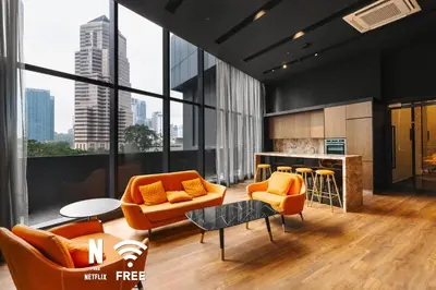 a living room with orange chairs and a counter at 1BR| Rooftop Twin Towers View l Near LRT in Kuala Lumpur