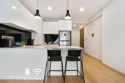a kitchen with a counter and two bar stools at Comfy 1BR with Twin Towers View in Kuala Lumpur