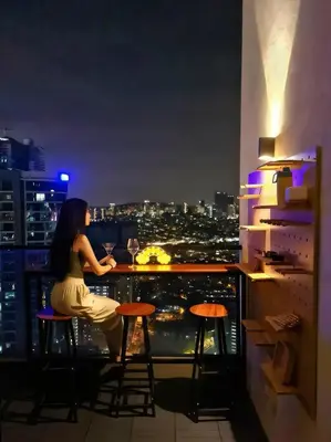 a woman sitting at a bar on top of a building at The Establishment - Menara Teguh Bangsar in Kuala Lumpur