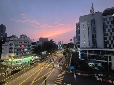 a city street with buildings and a sunset in the background at Homigo - PWTC in Kuala Lumpur