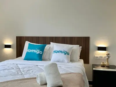 a bedroom with a bed with blue and white pillows at Homigo - PWTC in Kuala Lumpur