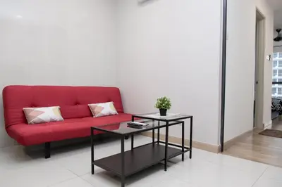 a red couch in a living room with a table at KL Gateway Bangsar by Sleepy Bear in Kuala Lumpur