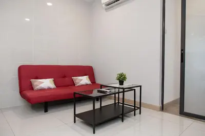 a red couch sitting in a room with a table at KL Gateway Bangsar by Sleepy Bear in Kuala Lumpur