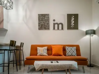 an orange couch in a living room with a table at Scenic Living Homestay Studio in Kuala Lumpur