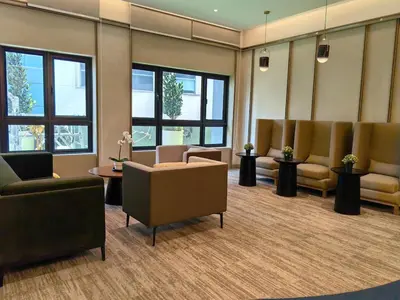 a waiting room with chairs and tables and windows at TRX Agile Bukit Bintang Deluxe 8 pax Family Suites in Kuala Lumpur