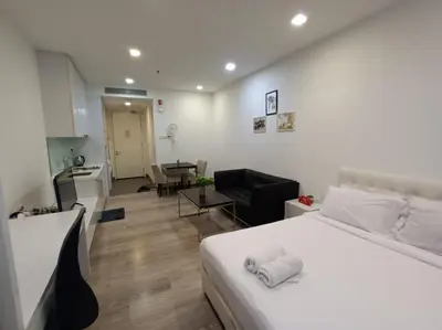 a bedroom with a white bed and a living room at AK Residence in Kuala Lumpur