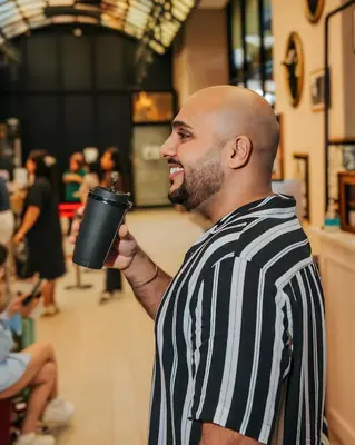 a man in a striped shirt holding a cup at Scarletz Luxury Suites KLCC in Kuala Lumpur