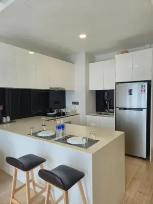 a kitchen with two bar stools and a refrigerator at Star Residence Sky World KLCC in Kuala Lumpur