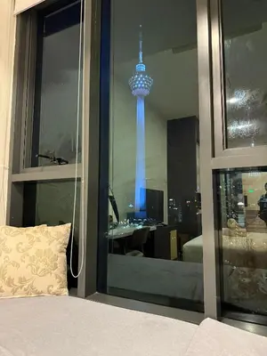 a bedroom with a view of a tower through a window at Cyelonz Suites in Kuala Lumpur