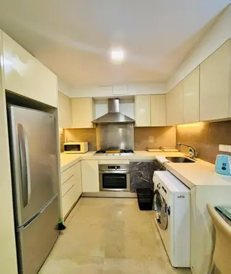 a kitchen with white cabinets and a silver refrigerator at Bukit Bintang Fairlane suite by Rose in Kuala Lumpur