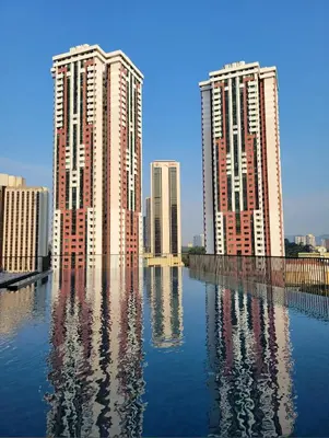 two tall buildings are reflected in the water at Cozy Chambers Studio KLCC Grand Opening Sale in Kuala Lumpur