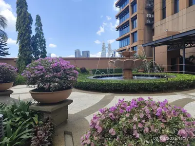 a fountain in the middle of a courtyard with flowers at The Golden Suites at Berjaya Times Square Kuala Lumpur in Kuala Lumpur