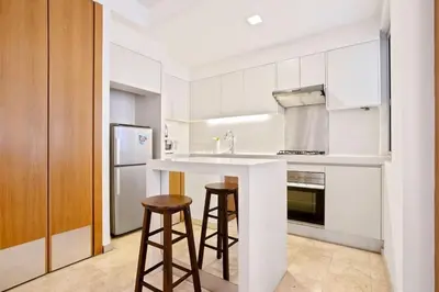 a kitchen with white cabinets and a counter with stools at My Habitat KL in Kuala Lumpur