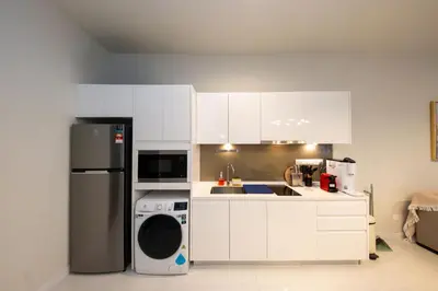 a kitchen with white cabinets and a black refrigerator at La Gente X Pavilion Embassy Serviced Suites in Kuala Lumpur
