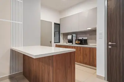 a kitchen with wooden cabinets and a white counter top at Trendy 3BR MVertica Near MRT by RumaBnB in Kuala Lumpur