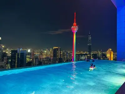 a man in a pool on the roof of a building with a city at The Platinum kuala lumpur By MAJU in Kuala Lumpur