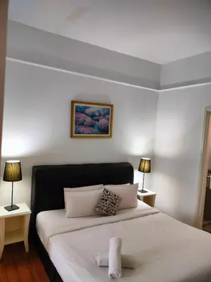 a bedroom with a large white bed with two lamps at Quitecove Service Suite at Times Square KL in Kuala Lumpur