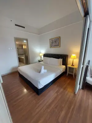 a bedroom with a large white bed and wooden floors at Quitecove Service Suite at Times Square KL in Kuala Lumpur